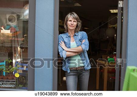 Woman in shop doorway, arms crossed looking at camera View Large Photo Image Stock Photo - Woman in shop doorway, arms crossed looking at camera. Fotosearch