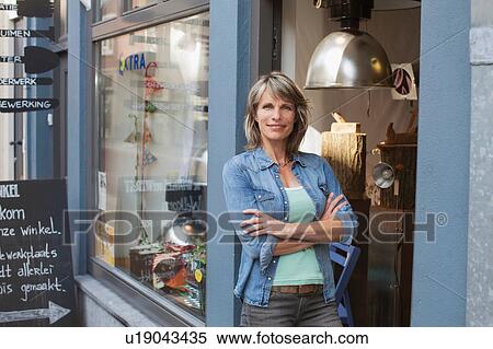 Woman in shop doorway, arms crossed looking at camera smiling View Large Photo Image Stock Photography - Woman in shop doorway, arms crossed looking at camera smiling. Fotosearch