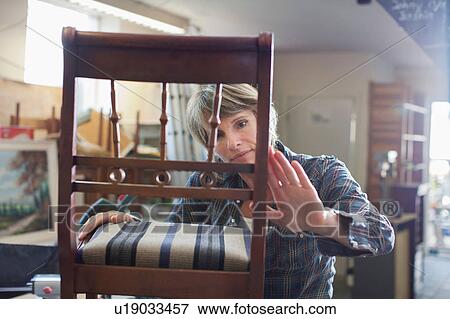 Stock Photo - Woman in workshop examining chair. Fotosearch