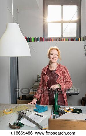 Woman in workshop wearing leather dress looking at camera smiling View Large Photo Image Stock Photograph - Woman in workshop wearing leather dress looking at camera smiling. Fotosearch
