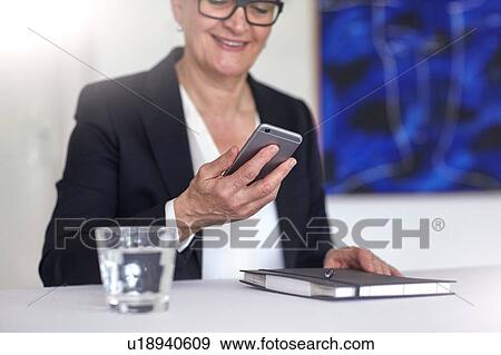 Woman looking at smartphone smiling View Large Photo Image Stock Photo - Woman looking at smartphone smiling. Fotosearch