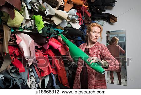 Stock Image - Woman making selection from stack of leather skins. Fotosearch