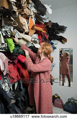 Stock Photo - Woman making selection from stack of leather skins. Fotosearch