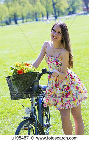 Woman on bicycle with flowers in basket View Large Photo Image Stock Image - Woman on bicycle with flowers in basket. Fotosearch