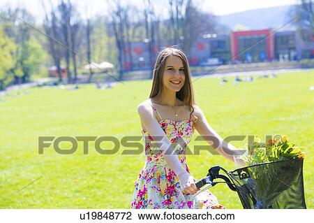 Woman on bicycle with flowers in basket View Large Photo Image Stock Image - Woman on bicycle with flowers in basket. Fotosearch