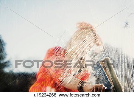 Stock Photo - Woman outdoors cleaning soapy window with squeegee. Fotosearch