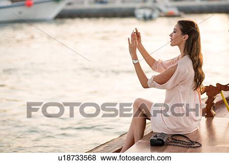 Woman photographing on smartphone on boat at Dubai marina, United Arab Emirates View Large Photo Image Stock Photo - Woman photographing on smartphone on boat at Dubai marina, United Arab Emirates. Fotosearch