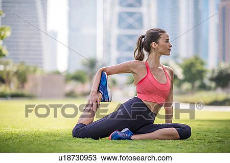Stock Image - Woman practicing yoga pose in park, Dubai, United Arab Emirates. Fotosearch