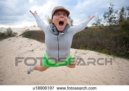 Stock Photo - Woman pulling a face whilst jumping mid air, Israel. Fotosearch