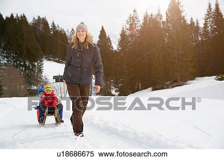 Woman pulling sons on toboggan in snow covered landscape, Elmau, Bavaria, Germany View Large Photo Image Stock Photography - Woman pulling sons on toboggan in snow covered landscape, Elmau, Bavaria, Germany. Fotosearch