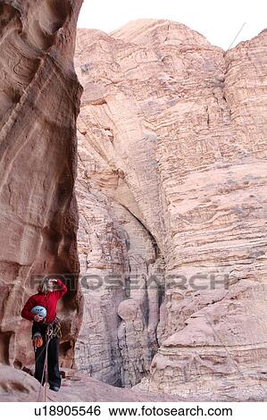 Stock Photograph - Woman rappelling at rock face, Wadi Rum, Jordan. Fotosearch