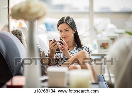Woman reclining on hotel room sofa using smartphone, Dubai, United Arab Emirates View Large Photo Image Picture - Woman reclining on hotel room sofa using smartphone, Dubai, United Arab Emirates. Fotosearch