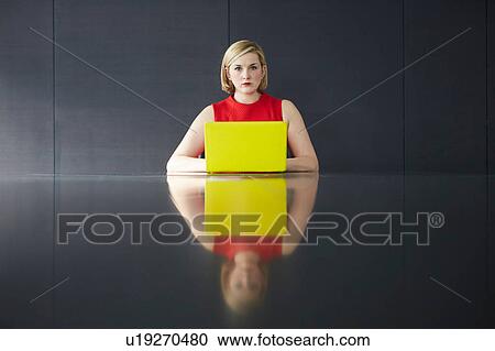 Woman sitting at desk with yellow laptop looking at camera View Large Photo Image Stock Image - Woman sitting at desk with yellow laptop looking at camera. Fotosearch