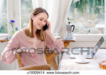 Woman sitting at table making telephone call View Large Photo Image Picture - Woman sitting at table making telephone call. Fotosearch