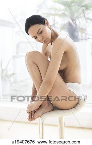 Stock Photograph - Woman sitting on a chair in underwear. Fotosearch