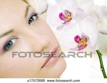Stock Photo - Woman smelling orchid flowers. Fotosearch