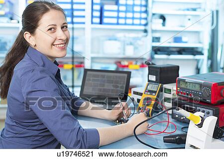 Stock Image - Woman soldering a printed circuit board. Fotosearch
