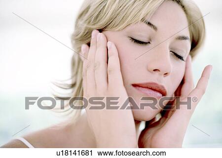 Stock Image - Woman touching her face. Fotosearch