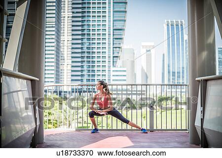 Stock Image - Woman training, stretching on balcony, Dubai, United Arab Emirates. Fotosearch