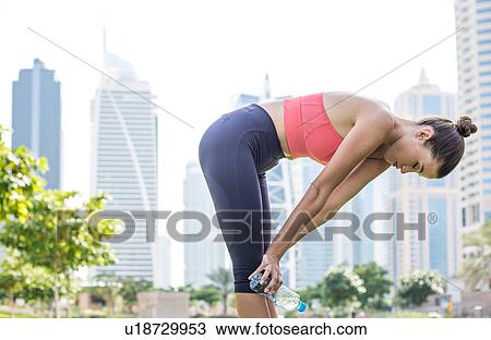 Stock Image - Woman training, taking a break in park, Dubai, United Arab Emirates. Fotosearch