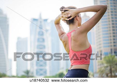 Woman training, twisting with hands behind head in park, Dubai, United Arab Emirates View Large Photo Image Stock Image - Woman training, twisting with hands behind head in park, Dubai, United Arab Emirates. Fotosearch