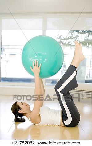 Stock Image - Woman using exercise ball. Fotosearch