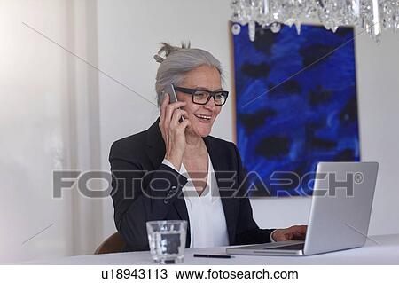Woman using laptop making telephone call on smartphone View Large Photo Image Stock Image - Woman using laptop making telephone call on smartphone. Fotosearch