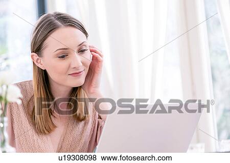 Stock Photo - Woman using laptop smiling. Fotosearch