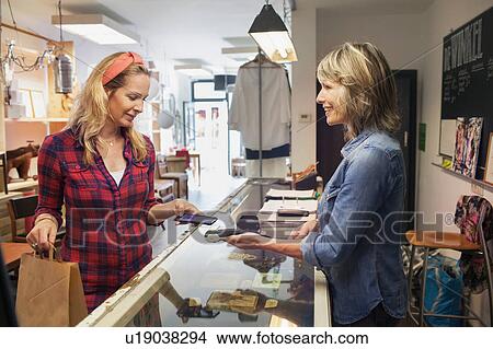 Woman using smartphone to make contactless payment on smartphone View Large Photo Image Picture - Woman using smartphone to make contactless payment on smartphone. Fotosearch
