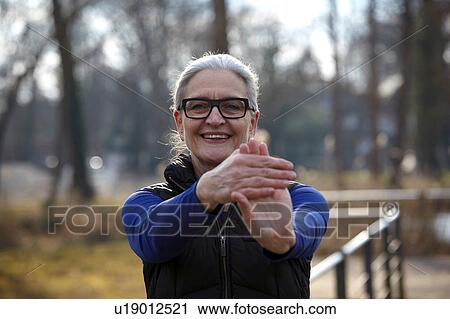 Stock Image - Woman wearing glasses arm out stretching hand, looking at camera smiling. Fotosearch