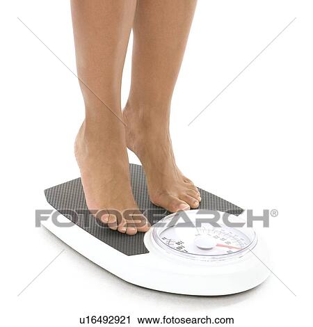 Stock Image - Woman weighing herself. Fotosearch