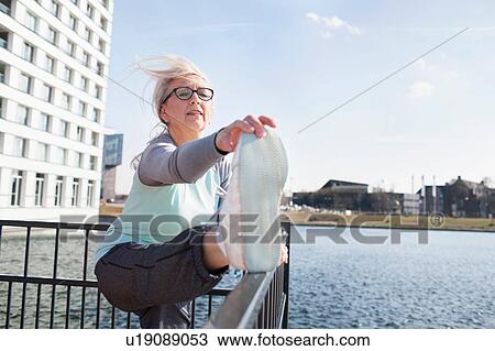 Woman with leg raised on railings stretching foot View Large Photo Image Stock Image - Woman with leg raised on railings stretching foot. Fotosearch