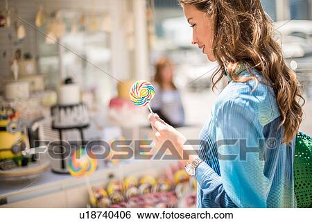 Stock Photograph - Woman with lollipop from sweet stall, Dubai, United Arab Emirates. Fotosearch
