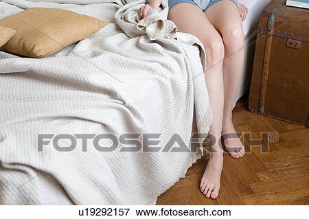 Womans legs sitting on bed View Large Photo Image Stock Photo - Womans legs sitting on bed. Fotosearch