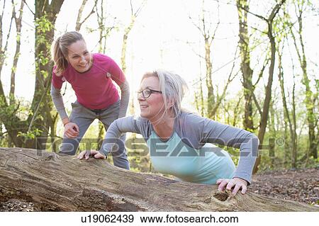 Stock Photo - Women in forest doing press ups against fallen tree. Fotosearch