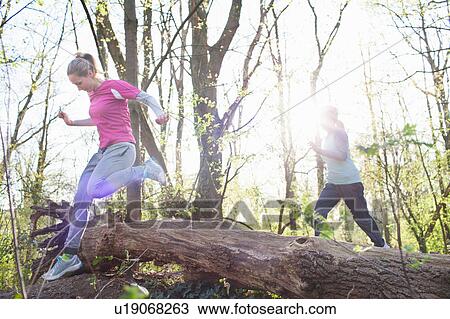 Women in forest jumping over fallen tree View Large Photo Image Stock Image - Women in forest jumping over fallen tree. Fotosearch