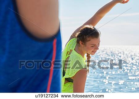 Women in front of ocean bending over sideways stretching View Large Photo Image Picture - Women in front of ocean bending over sideways stretching. Fotosearch