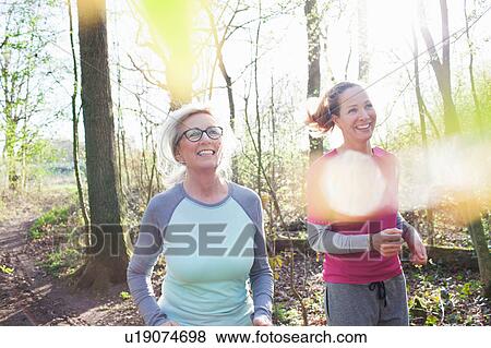 Stock Photo - Women jogging in forest smiling. Fotosearch