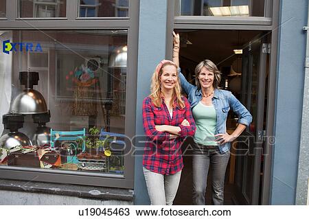 Women standing in shop doorway looking at camera smiling View Large Photo Image Stock Image - Women standing in shop doorway looking at camera smiling. Fotosearch