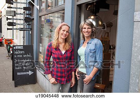 Stock Photo - Women standing in shop doorway looking at camera smiling. Fotosearch