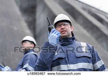 Worker using walkie talkie at foot of dam at hydroelectric power station View Large Photo Image Stock Photo - Worker using walkie talkie at foot of dam at hydroelectric power station. Fotosearch