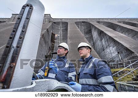 Stock Photo - Workers at foot of dam at hydroelectric power station. Fotosearch