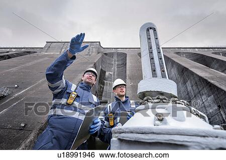 Workers at foot of dam at hydroelectric power station View Large Photo Image Stock Photograph - Workers at foot of dam at hydroelectric power station. Fotosearch