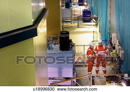 Stock Image - Workers in hydroelectric power station. Fotosearch