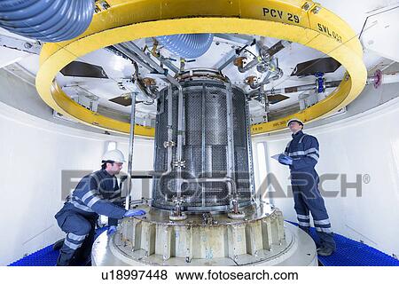 Stock Photo - Workers inspecting turbine housing in hydroelectric power station. Fotosearch