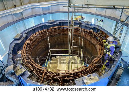 Stock Image - Workers maintaining generator in hydroelectric power station. Fotosearch