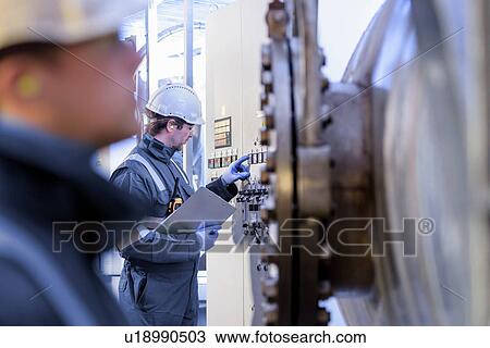 Stock Image - Workers with machinery in hydroelectric power station. Fotosearch