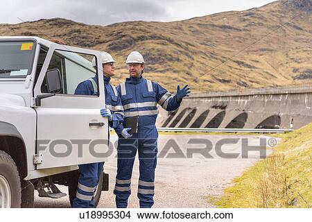 Picture - Workers with utility vehicle by dam at hydroelectric power station. Fotosearch