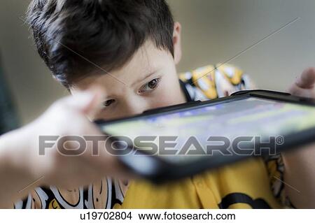 Young boy playing on handheld device View Large Photo Image Picture - Young boy playing on handheld device. Fotosearch
