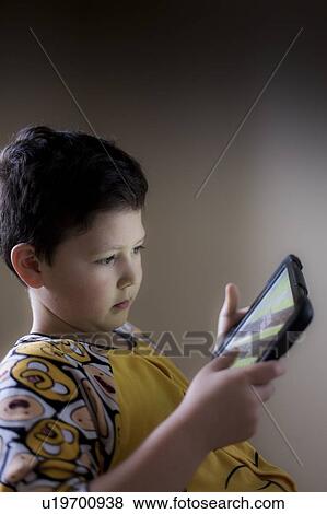 Young boy playing on handheld device View Large Photo Image Stock Photo - Young boy playing on handheld device. Fotosearch